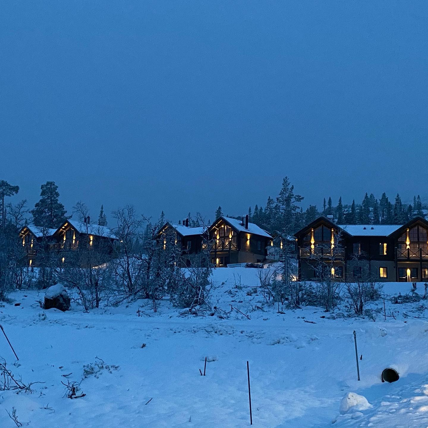 Stugor i snölandskap med belysning på natten